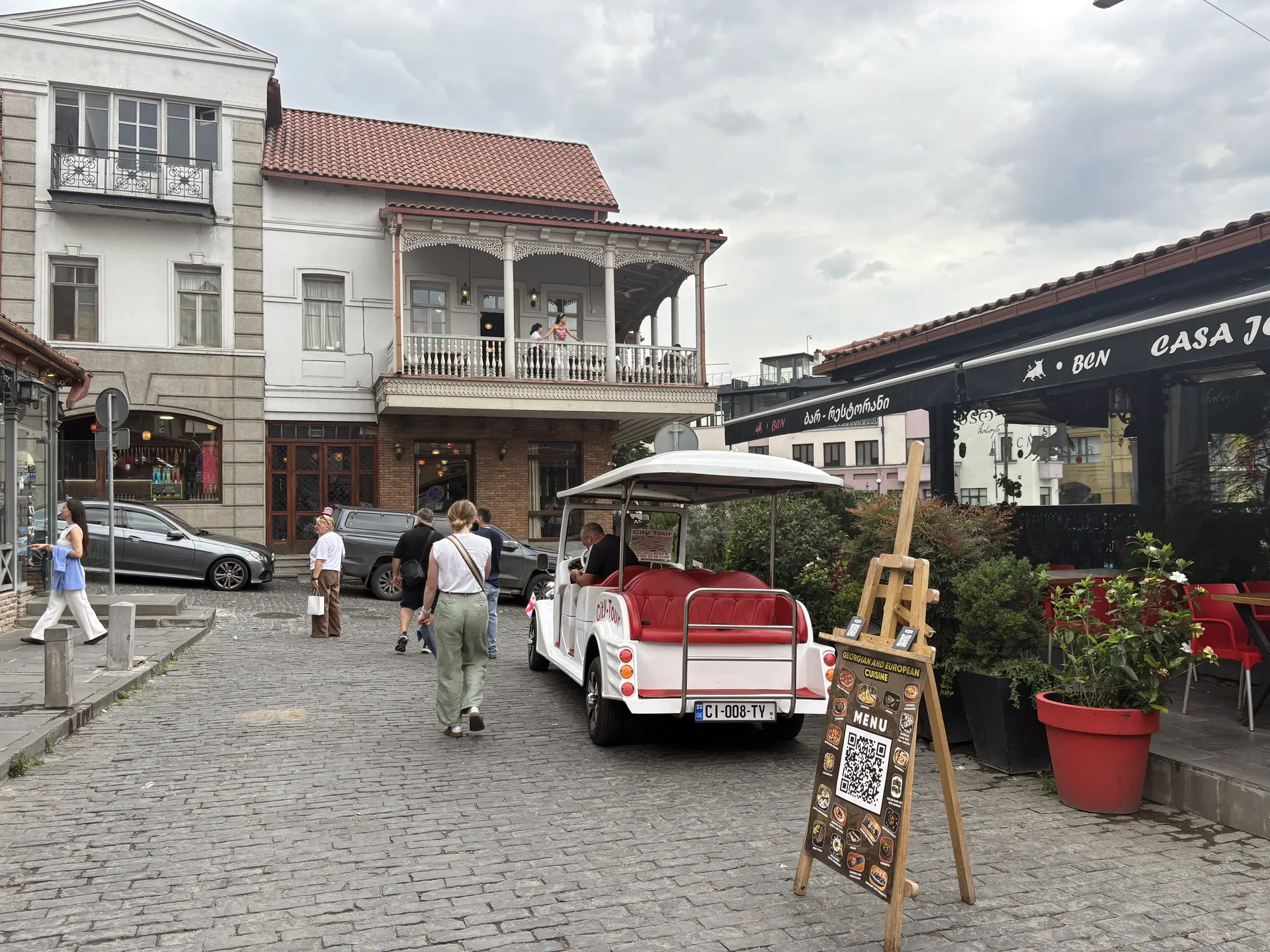 Old Town street with café terraces and a small vehicle in Tbilisi